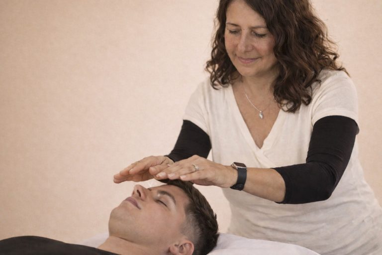 Frau führt eine Reiki Behandlung durch – energetische Heilung in der Praxis Rosmary WEISS